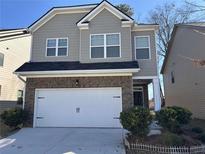 Charming two-story home with a brick and gray facade, attached two-car garage and well-maintained landscaping at 11978 Lovejoy Crossing Way, Hampton, GA 30228