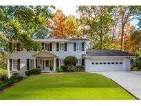 Charming white brick home featuring manicured lawn and mature trees in a desirable neighborhood at 870 Richmond Hill Dr, Marietta, GA 30068