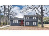 Charming two-story home featuring a gray exterior, white-framed windows, and a striking red front door at 2710 Beaver Creek Xing, Powder Springs, GA 30127