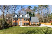 Traditional red brick two story home featuring a well manicured front yard, dormers and black shutters at 735 Princeton Mill Run, Marietta, GA 30068