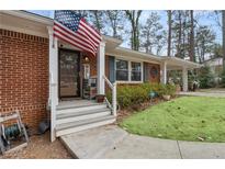 Charming brick home featuring a welcoming front porch and American flag at 3245 Westmart Ln, Atlanta, GA 30340