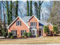 Charming brick home featuring black shutters, a manicured lawn, and mature trees at 675 Ashley Laine Walk, Lawrenceville, GA 30043
