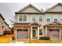Charming townhome features a brick-accented facade, single-car garage, and inviting entrance with olive-colored front door at 7750 Carnegie Dr, Fairburn, GA 30213