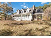 Charming home featuring a full front porch, screened in side porch, and mature trees at 935 Old Loganville Rd, Loganville, GA 30052