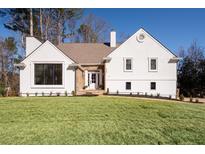 Charming home featuring a manicured lawn, stone accents, a brown shingled roof, and a bright white facade at 1986 Willeo Creek Pt, Marietta, GA 30068
