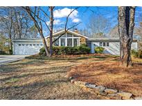 Charming home with a two-car garage and lush landscaping, complemented by a stone accent wall and mature trees at 1760 Canton Hills Cir, Marietta, GA 30062