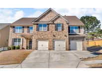 Inviting two-story brick home featuring a three-car garage, lush lawn, and a classic design at 4869 Locherby Dr, Fairburn, GA 30213