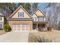 Charming two-story home boasts a stone and siding exterior with a two-car garage and well-maintained front yard at 3158 Arbor Oaks Way, Snellville, GA 30039