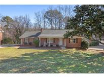 Charming brick ranch home with a well-manicured front yard, mature trees, and a cozy front porch at 3540 Honeycomb Se Dr, Conyers, GA 30094