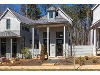 Charming modern home featuring a metal roof, white columns, and well-maintained landscaping at 135 Mado Ln, Chattahoochee Hills, GA 30268