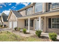 Charming two-story brick home with a two-car garage, covered porch, and manicured lawn at 165 Kentwood Springs Dr, Hampton, GA 30228