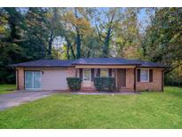 Charming single-story brick home featuring a well-maintained lawn, and attached garage at 5411 Louis Xiv Ln, Atlanta, GA 30349