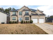 Charming two-story brick home with well-manicured landscaping, attached two-car garage, and inviting front entrance at 4526 Warren Mill Trl, Ellenwood, GA 30294