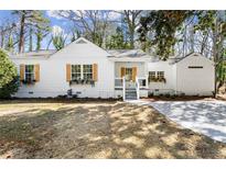 Charming home with white siding, wooden shutters, and a well-manicured lawn and long concrete driveway at 1428 Pinehurst Sw Dr, Atlanta, GA 30311