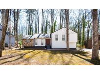 Charming home featuring stone accents, white siding, and a well-maintained front yard surrounded by mature trees at 5199 Mainstreet Park Dr, Stone Mountain, GA 30088