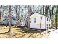 Charming home boasts updated siding and dark trim accents, surrounded by beautiful mature trees at 5199 Mainstreet Park Dr, Stone Mountain, GA 30088