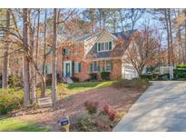 Charming two-story brick home with green shutters and well-manicured front yard on a sunny day at 1880 Meadowchase Ct, Snellville, GA 30078