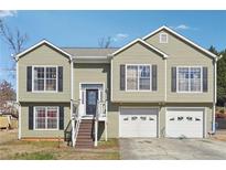 Charming split-level home featuring light-green siding, black shutters, and a convenient two-car garage at 760 Josh Ln, Lawrenceville, GA 30045