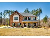 Charming two-story home with brick accents, a covered porch and a well-maintained landscaped front yard at 60 Bridgemill Dr, Covington, GA 30014