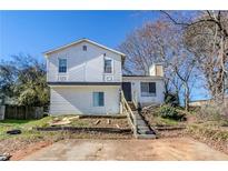 Two-story home featuring white siding, front stairs, and an unfinished front yard at 4821 Mainstreet Valley Trce, Stone Mountain, GA 30088