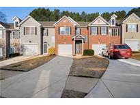 A view of a brick townhome with a single car garage and a long driveway at 418 Lantern Wood Dr, Scottdale, GA 30079