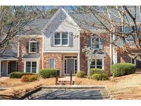 Charming townhome featuring a brick facade, complemented by stylish gray accents, lush landscaping, and inviting entrance at 312 River Glen Dr, Roswell, GA 30075