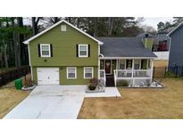 Charming two-story home with a well-manicured lawn, inviting front porch, and a convenient one car garage at 2102 Bedford Ct, Lithonia, GA 30058