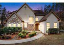 Charming home featuring a stone facade, arched windows, manicured landscaping, and a welcoming walkway at 2557 Sixes Rd, Canton, GA 30114