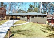 Charming home featuring a well-maintained lawn, gray brick, long driveway, and a convenient carport at 2569 Woodhill Ln, Atlanta, GA 30344