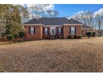 Charming red brick home with a dark roof, set on a spacious lawn with mature trees and manicured bushes at 1450 Brandy Shoals Se Dr, Conyers, GA 30013