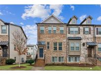 Charming brick townhome featuring a welcoming front entrance, multiple windows and professional landscaping at 4447 Kerrington Ave, Sugar Hill, GA 30518