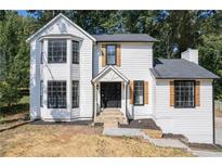 Charming two-story home featuring black windows, shutters, and a well-maintained, landscaped yard at 557 Old Friar Tuck Ln, Stone Mountain, GA 30087