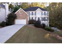 Two-story home featuring a stone facade, black shutters, a well-manicured lawn and an attached two-car garage at 314 Lake Bluff Ct, Suwanee, GA 30024