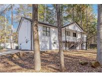 Charming home featuring a quaint front porch and stairs nestled within a wooded landscape at 7155 Pineneedle Drive Sw, Covington, GA 30016