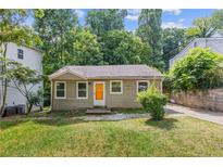 Charming single-story home featuring a well-maintained lawn, complemented by mature trees and an inviting orange front door at 2825 3Rd Sw Ave, Atlanta, GA 30315