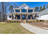 Charming two-story home featuring a welcoming front porch, stone accents, and manicured landscaping at 684 Old Cumming Rd, Sugar Hill, GA 30518