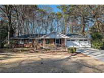 Charming brick home with a well-manicured lawn and two car garage nestled in a beautiful wooded neighborhood at 1888 Colt Dr, Atlanta, GA 30341