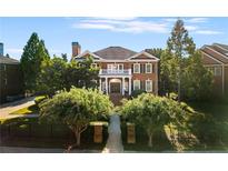 Charming brick home featuring mature trees, a second-story balcony, and a beautiful front yard at 5080 Riverlake Dr, Peachtree Corners, GA 30097