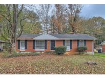 Charming brick home with a well-maintained lawn, dark shutters, and mature trees in a quiet neighborhood at 8309 Dunellen Ln, Jonesboro, GA 30238