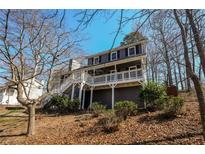 Charming two-story home features a spacious front porch with white railings and stairs, nestled among mature trees at 452 Springfield Dr, Woodstock, GA 30188