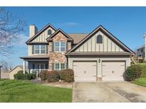 Charming two-story home featuring a stone facade, two-car garage, and well-maintained lawn at 6525 Oak Highlands Ct, Cumming, GA 30041