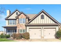 Charming two-story home featuring a stone facade, attached two-car garage, and meticulously maintained landscaping at 6525 Oak Highlands Ct, Cumming, GA 30041