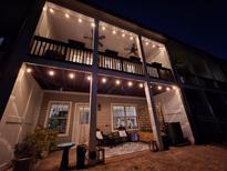 Cozy back porch at night featuring string lights, ceiling fans, and outdoor seating area at 10162 Windalier Way, Roswell, GA 30076
