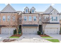 Beautiful townhome exterior with a brick facade, attached garages, and well-maintained landscaping at 10162 Windalier Way, Roswell, GA 30076