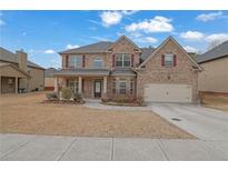 Charming brick two-story home with a well-manicured lawn, covered porch, and two-car garage at 2040 Browning Bend Ct, Dacula, GA 30019