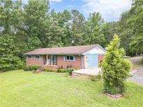Charming brick home with a cozy front porch and blue shutters, surrounded by lush greenery and mature trees at 5255 Post Rd, Winston, GA 30187