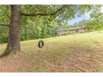 Lovely front yard features a mature tree and a tire swing at this brick home at 5255 Post Rd, Winston, GA 30187