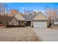 Charming single-story home with stone accents, a well-manicured lawn, and an attached two-car garage at 129 Windy Cir, Mcdonough, GA 30253