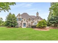 Charming brick home with lush front lawn, blue shutters, mature trees, and manicured landscaping at 165 Ansley Way, Roswell, GA 30075