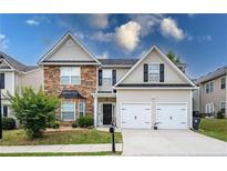 Charming two-story home featuring stone accents, a two-car garage, and a well-manicured lawn at 26 Crescent Ln, Dallas, GA 30157